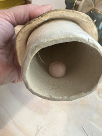 a person holding a clay pot with a ball in it