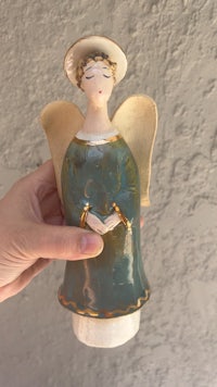 a person holding a ceramic angel figurine